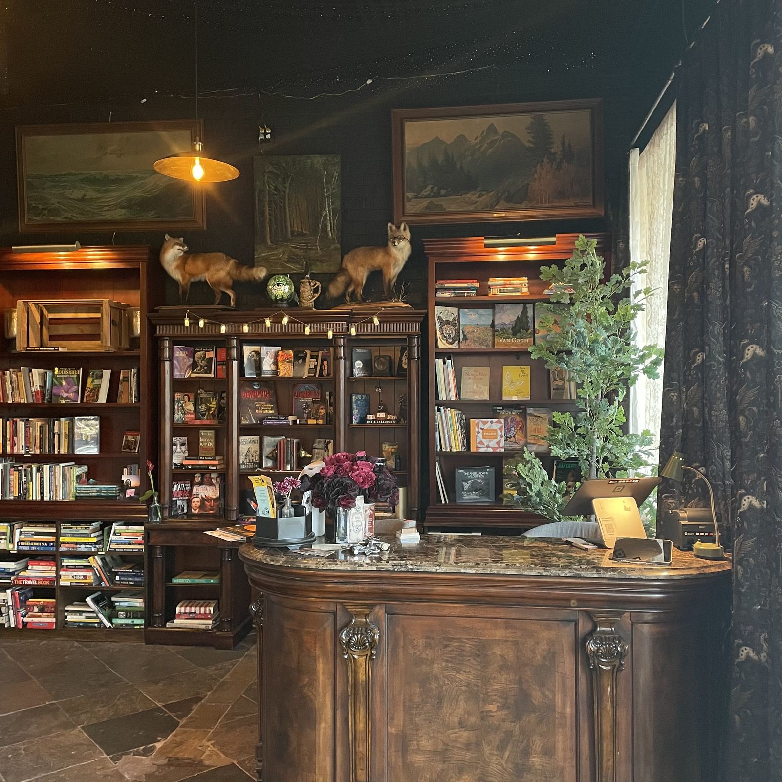 Carved wood front counter with marble top, surrounded by bookcases and landscape paintings